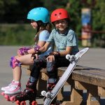 picture of two kids with roller skates and a skateboard in the park