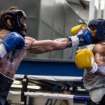 One boxer hit another boxer protected with head guard and groind guards in his head