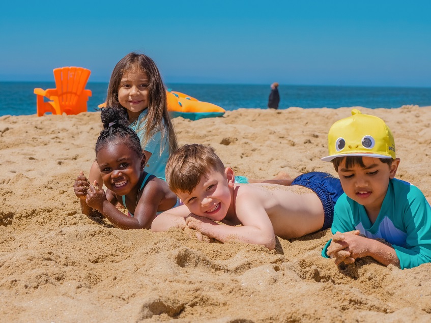 children laying on the sand at the beach