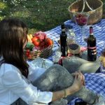 two girls sitting on grass with food and drink