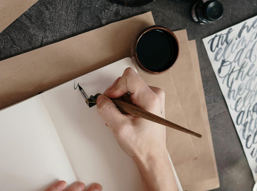 woman writing with a dip calligraphy pen 