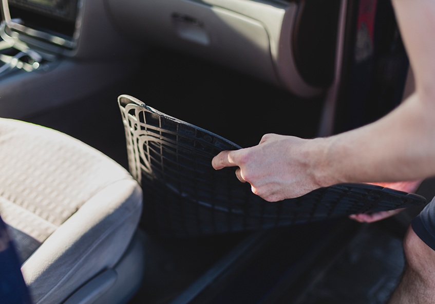 person putting on a new car mat